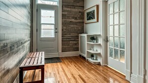A hallway with wooden flooring, a bench, a radiator, and a door with frosted glass panels.