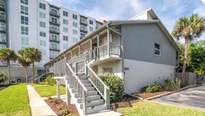 A two-story building with a balcony, a staircase, and a well-maintained lawn. - Downtown-Melbourne Beach-Dining-Cafes Walk to Everything (Melbourne)