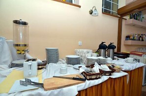 Una barra de buffet con platos, vasos y una estación de café.