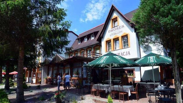 Un bâtiment traditionnel avec une enseigne indiquant « FAMILLE DWOKER » et des places assises à l’extérieur, protégées par des parasols.