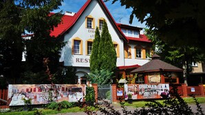 Un bâtiment à deux étages, avec un toit rouge et des murs blancs, portant l’inscription « RESTAURANT DE LA FAMILLE DWOREK ».