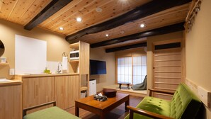 Um quarto aconchegante com teto de madeira, um sofá verde, uma mesa de madeira e uma televisão.