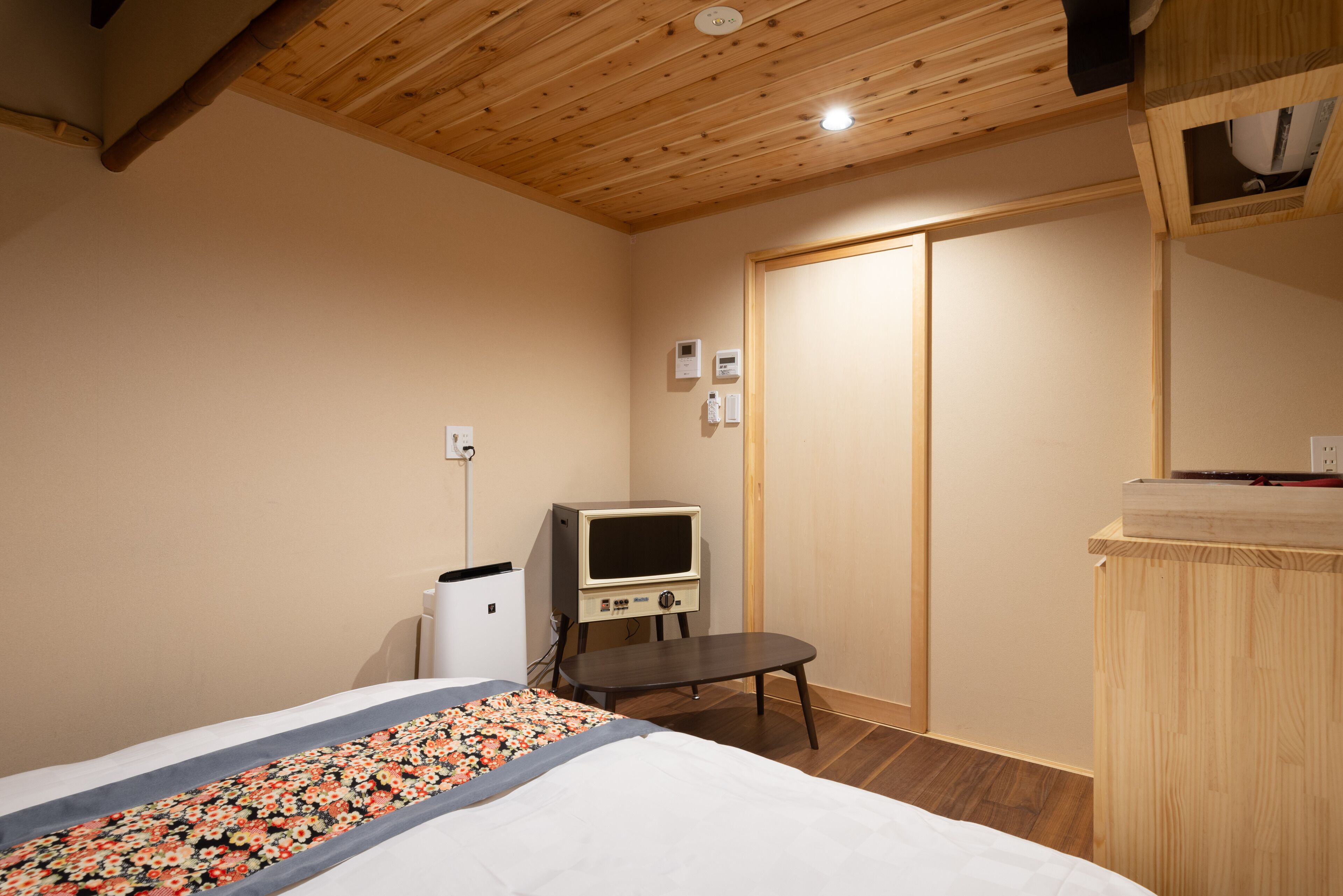 Ein Schlafzimmer mit einem Bett, einem kleinen Schreibtisch, einem Fernseher und einem Kleiderschrank.