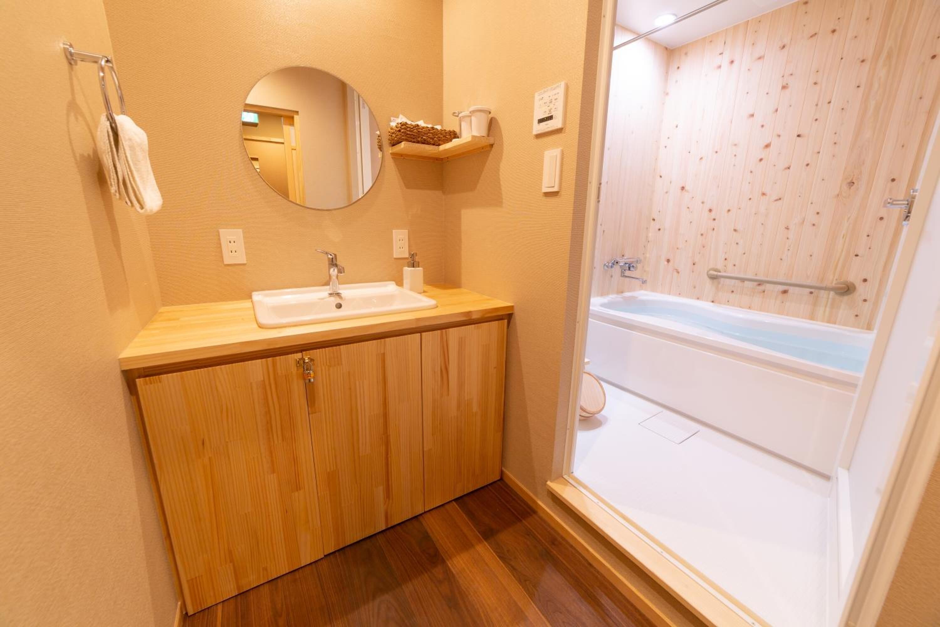 Un baño con tocador de madera, lavamanos, espejo y bañera.