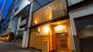 Um edifício japonês tradicional com entrada de madeira, uma porta deslizante e uma pequena estrutura de madeira na parte externa.