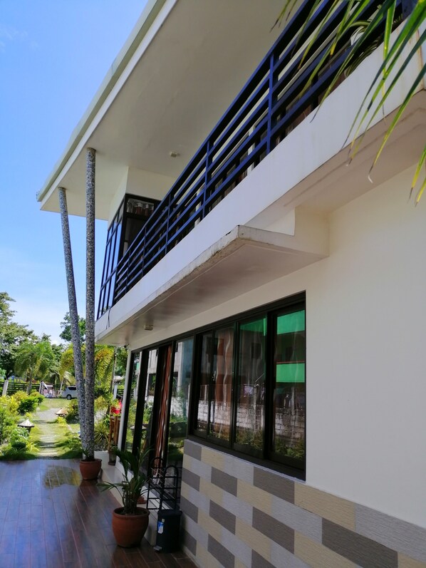 A modern building with a balcony, large windows, and potted plants. - Casa Herminia Baler (Baler)