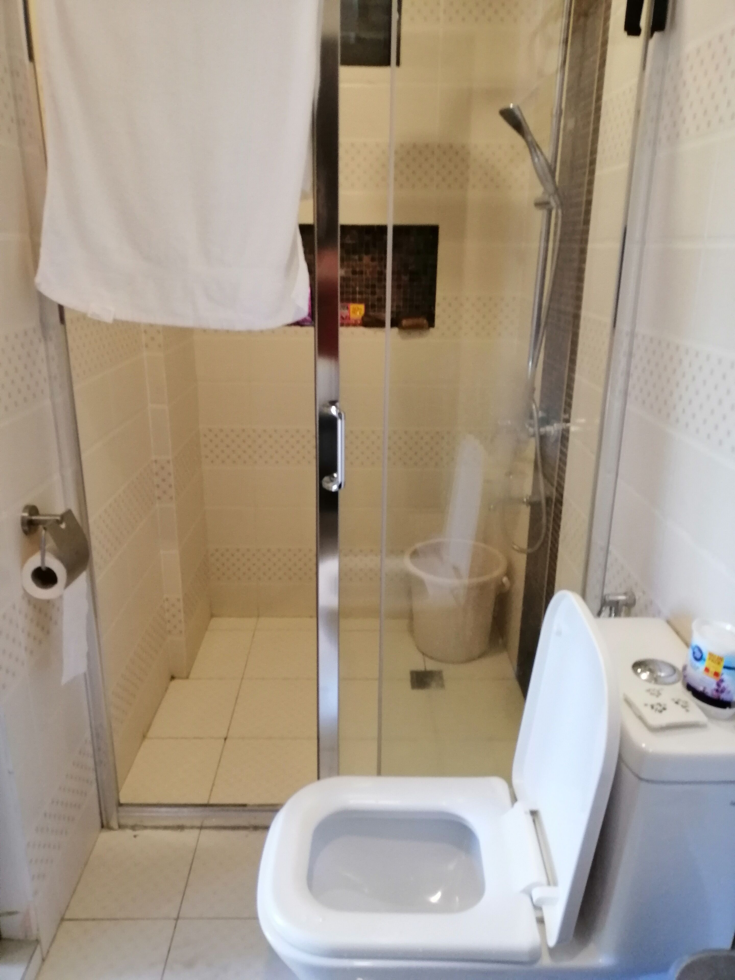 A bathroom with a glass-enclosed shower, a toilet, and a sink.