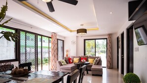 A modern living room with a sofa set, dining table, and large windows. - Casa Herminia Baler (Baler)