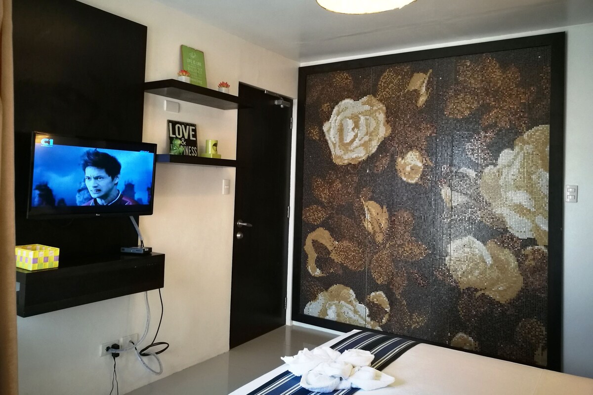 A modern living room with a television, a decorative wall, and a sofa.