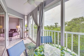 A balcony with a table and chairs, a sofa, and a view of greenery.
