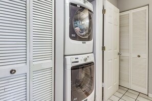 A laundry area with two stacked washing machines and a dryer, enclosed by white doors with horizontal louvered panels. - Pool Access, Walk to Manatee Beach: Coastal Condo (Holmes Beach)