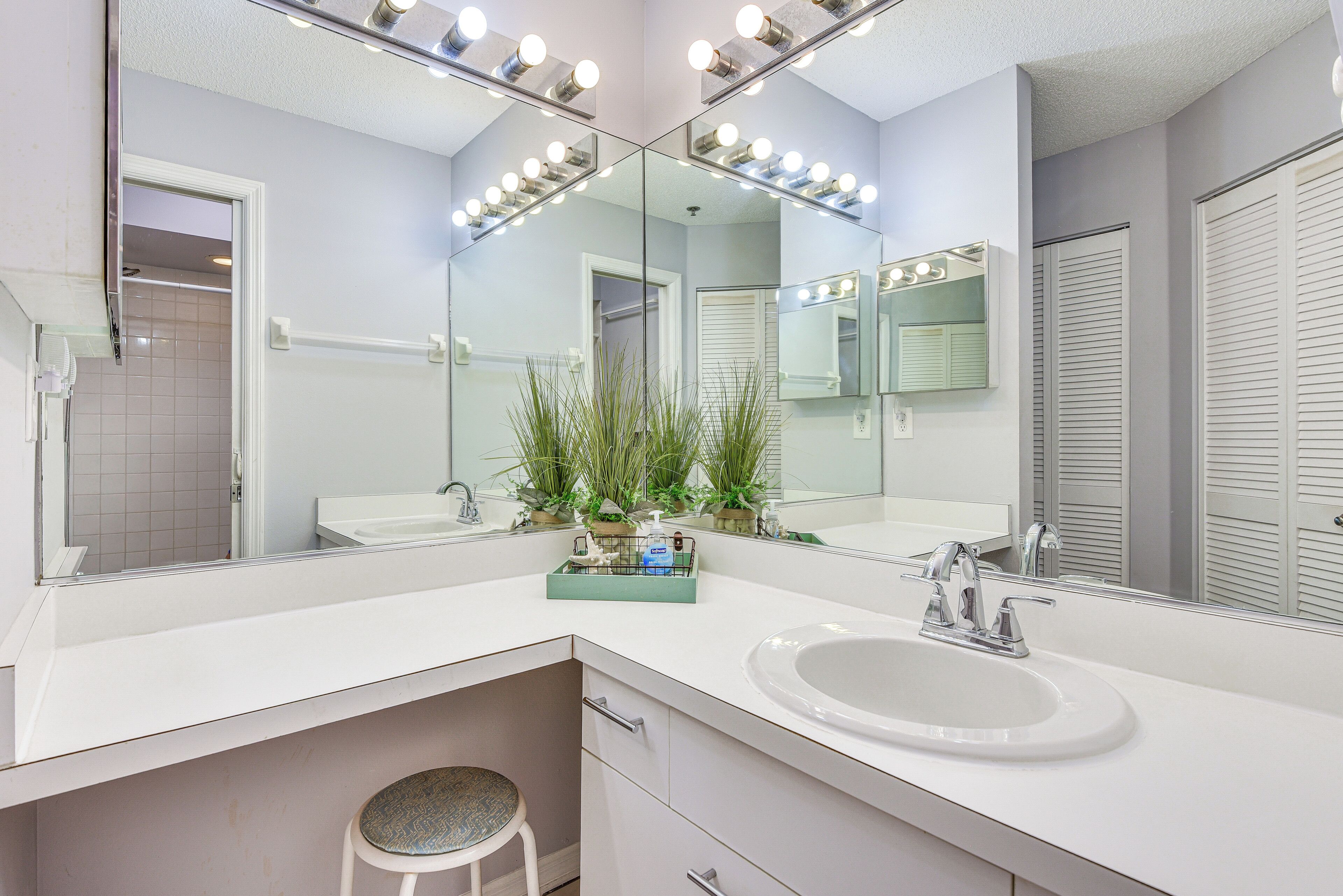 A bathroom with a vanity, sink, and mirrors.