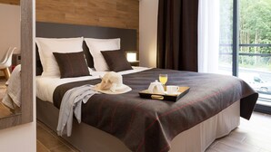 A modern hotel room with a large bed, a wooden headboard, and a view of the outdoors.