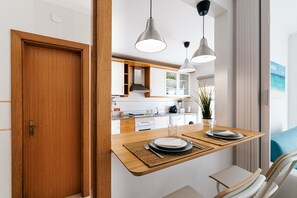 A modern kitchen with white cabinets, a wooden countertop, and hanging pendant lights. - Baleal Beachfront Apartment (Ferrel)
