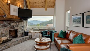 Una sala de estar acogedora con chimenea de piedra, sofá de cuero y televisor montado en la pared.
