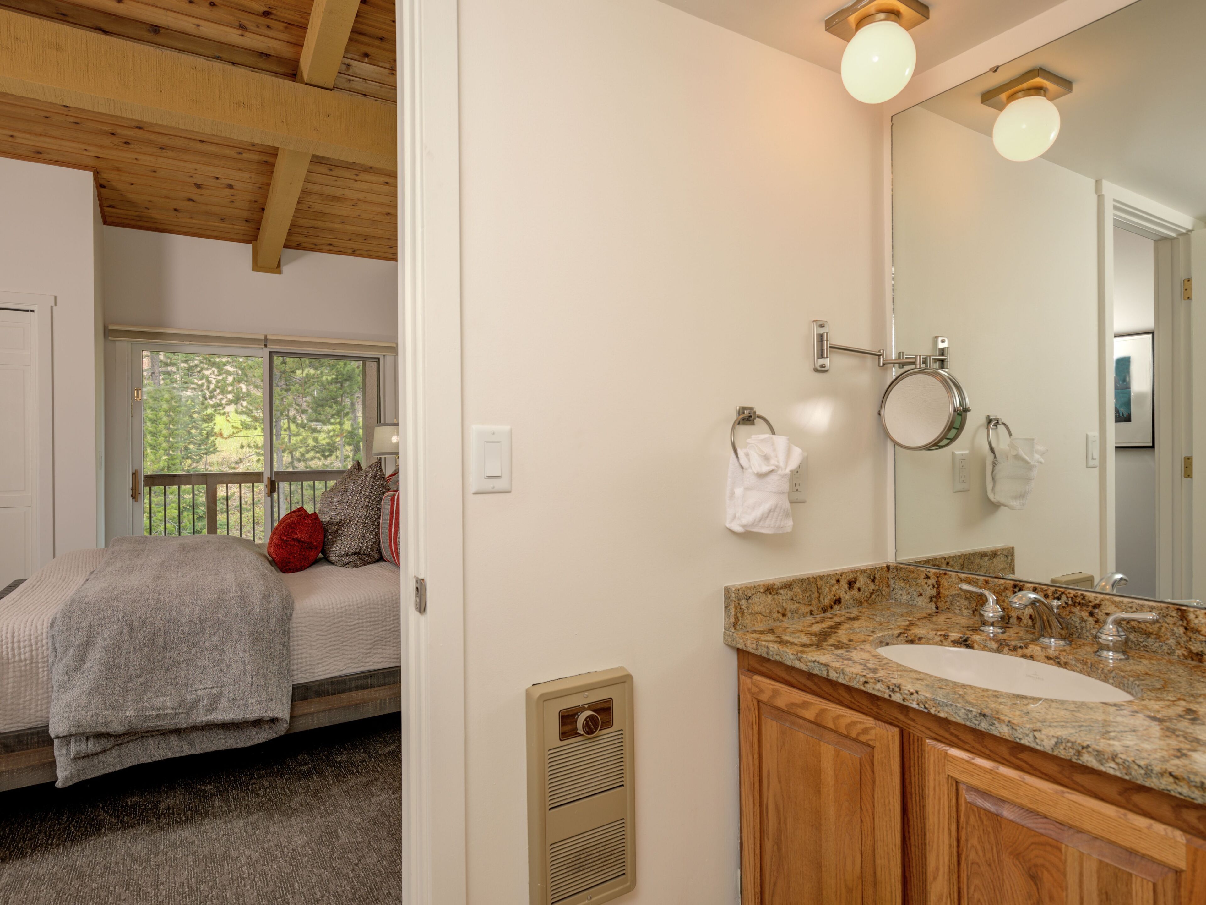 Une chambre à coucher avec un lit, une fenêtre et une salle de bain comprenant un lavabo et un miroir.