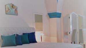 Un dormitorio con una cama grande, un techo con detalles azules, una pared blanca y una puerta.