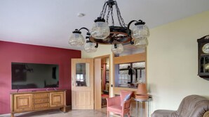 Un soggiorno con un mobile in legno, una televisione, un divano in pelle, una poltrona a dondolo e un lampadario.