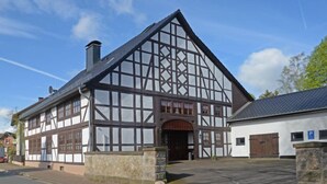 Un edificio tradizionale con struttura a graticcio, un'ampia entrata e un muro in pietra di fronte.