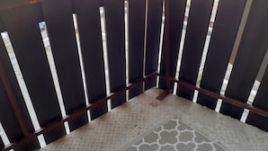 A corner of a balcony with a patterned floor mat and a wooden railing. - Homerez - Studio in Allos - mountain view (Allos)