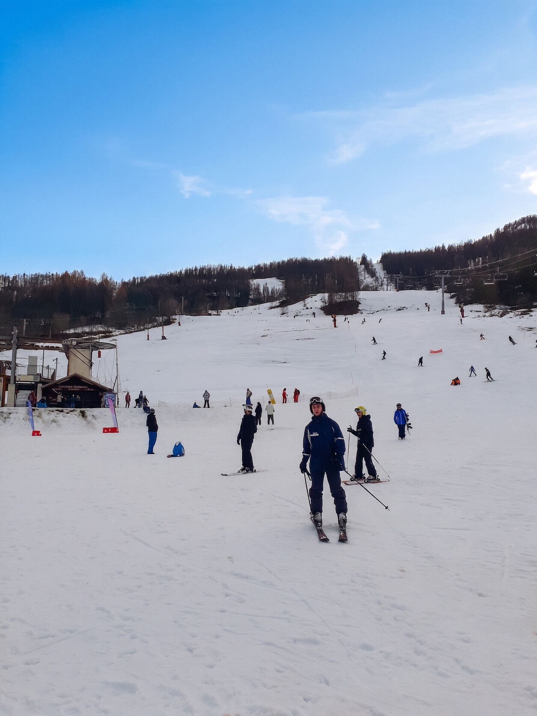 Een skipiste met skiërs en een skilift op de achtergrond.