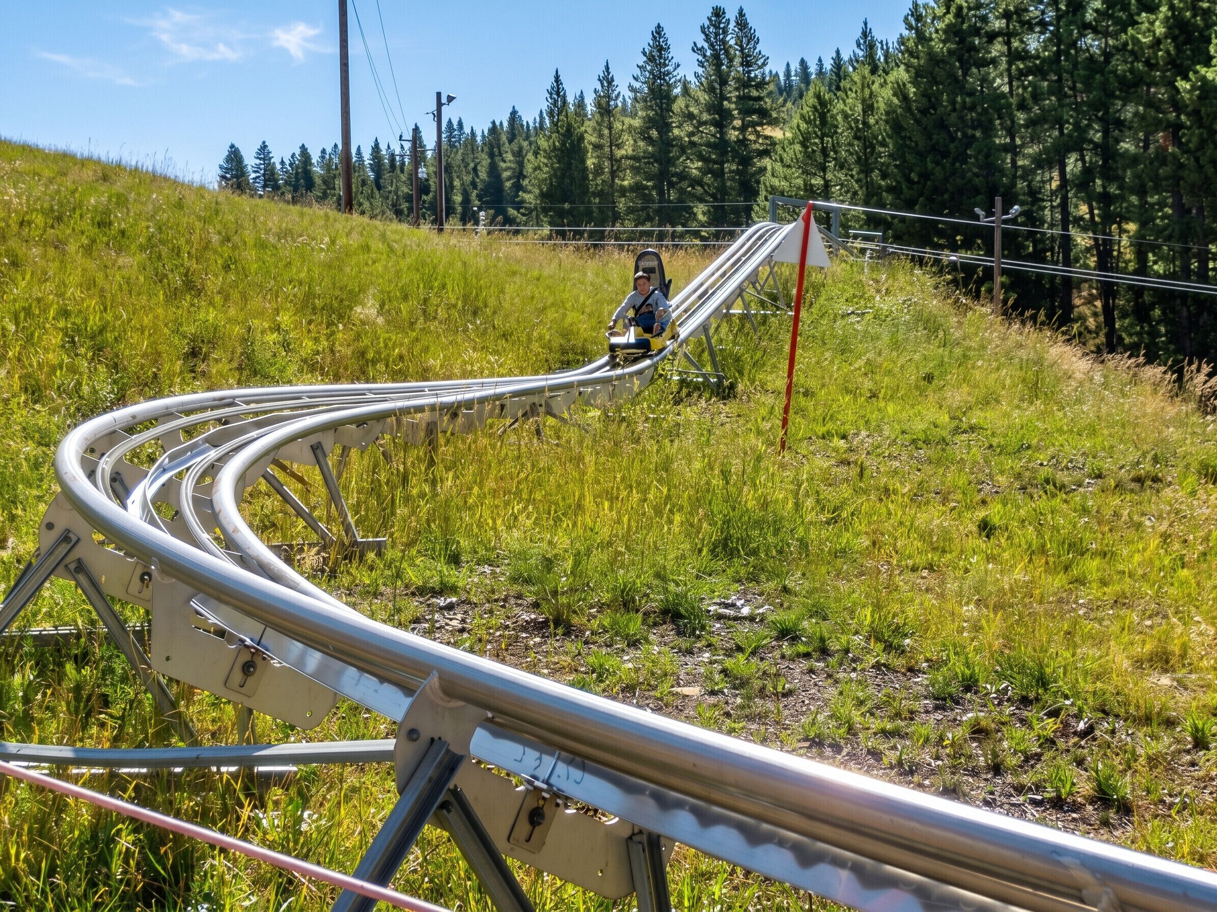 A metal spiral staircase in a grassy area with trees in the background.