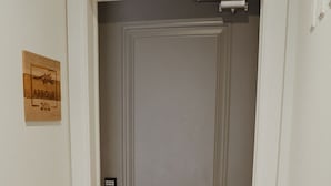 A closed door with a keypad lock, a small wooden plaque with the number 201, and a patterned rug on the floor.
