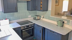 Eine Küche mit dunkelblauen Schränken, einem eingebauten Backofen, einem Toaster und einem Wasserkocher auf der Arbeitsplatte.