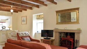 Ein Wohnzimmer mit Kamin, Fernseher und einem Essbereich mit Tisch und Stühlen.
