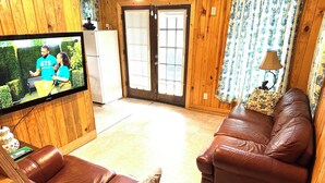 A living room with a television, two brown leather sofas, a wooden door, and a patterned curtain.