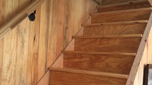A wooden staircase with a handrail and a wall-mounted light fixture.