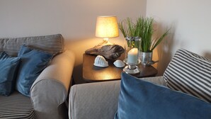 A cozy living room with striped sofas, a side table with a lamp, decorative shells, and a candle. - Sea view, balcony, 3 room apartment (Büsum)