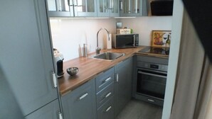 A compact kitchen with a microwave, sink, and oven. - Sea view, balcony, 3 room apartment (Büsum)