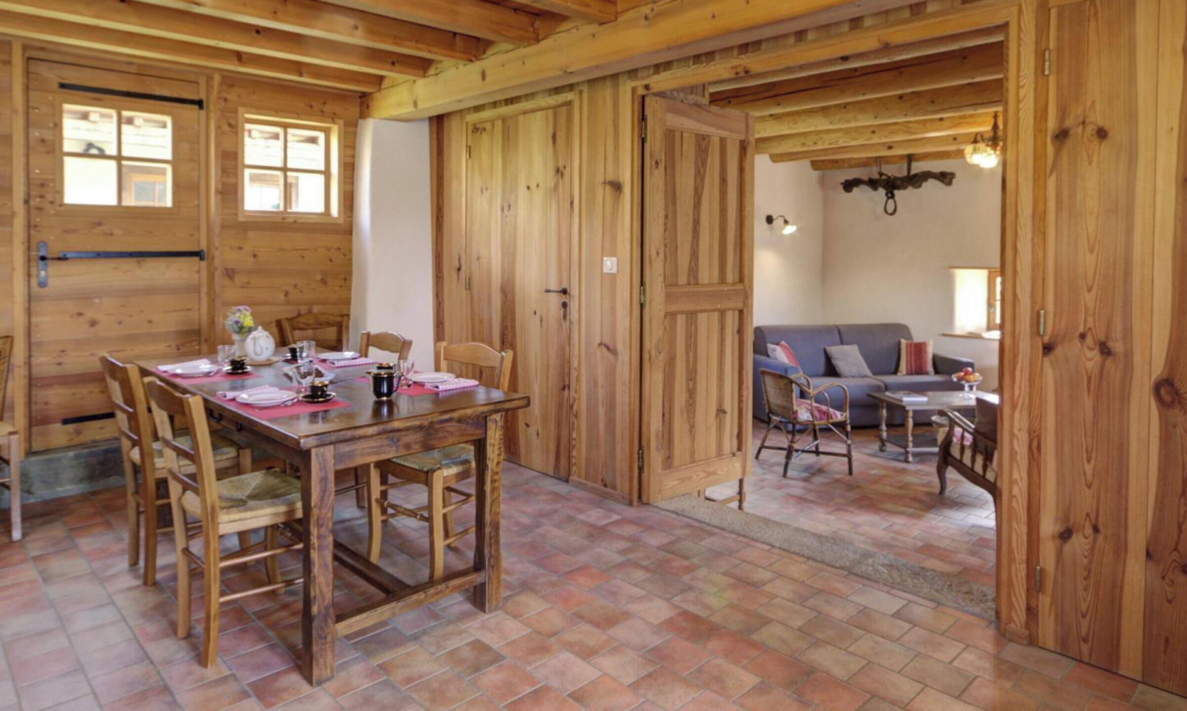 Un intérieur en bois comprenant une table à manger pour quatre personnes, un canapé et un fauteuil.