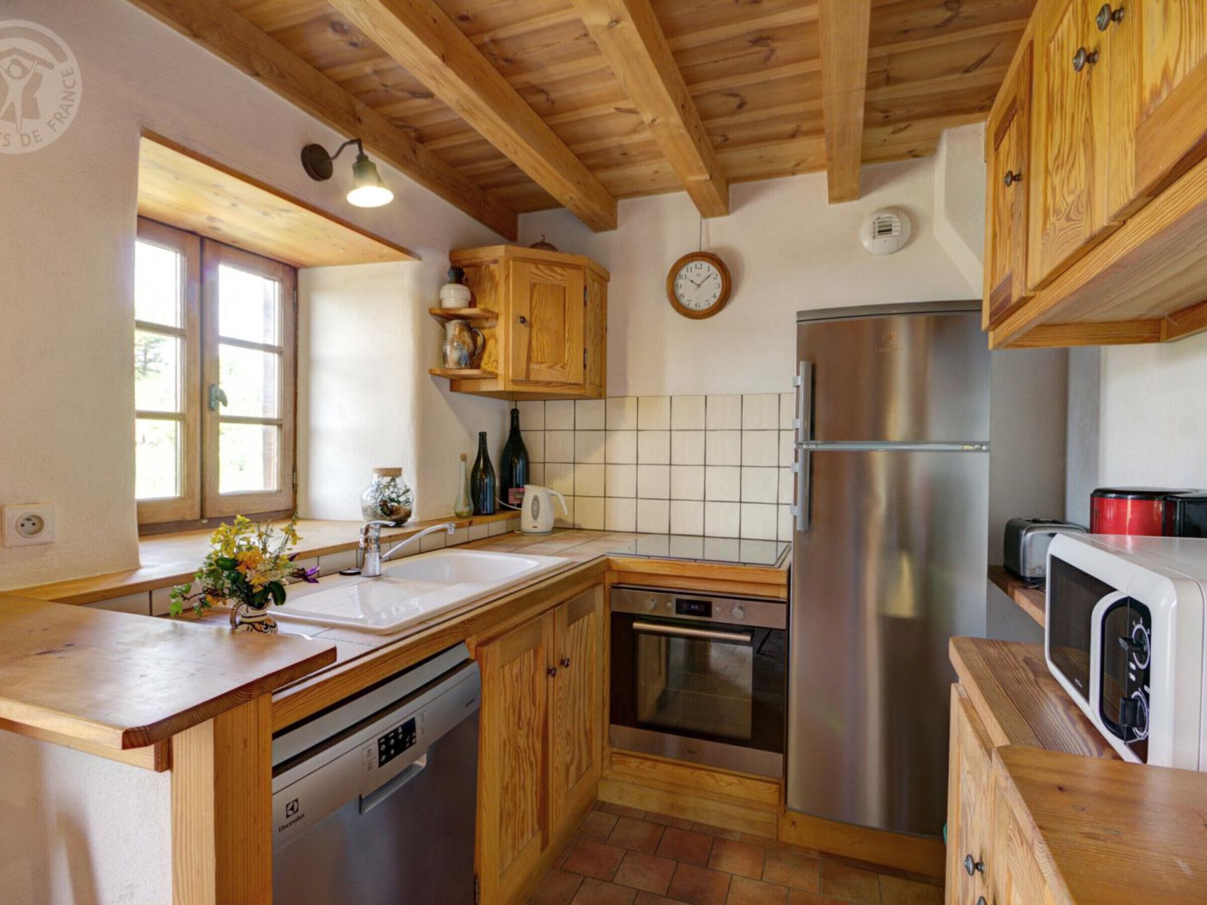 Une cuisine avec des meubles en bois, un réfrigérateur en acier inoxydable, un lave-vaisselle et un four à micro-ondes.