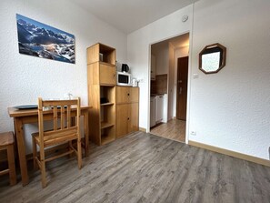 Una habitación con una mesa y sillas de madera, un armario empotrado de madera, un microondas y vistas a un paisaje montañoso a través de una ventana.