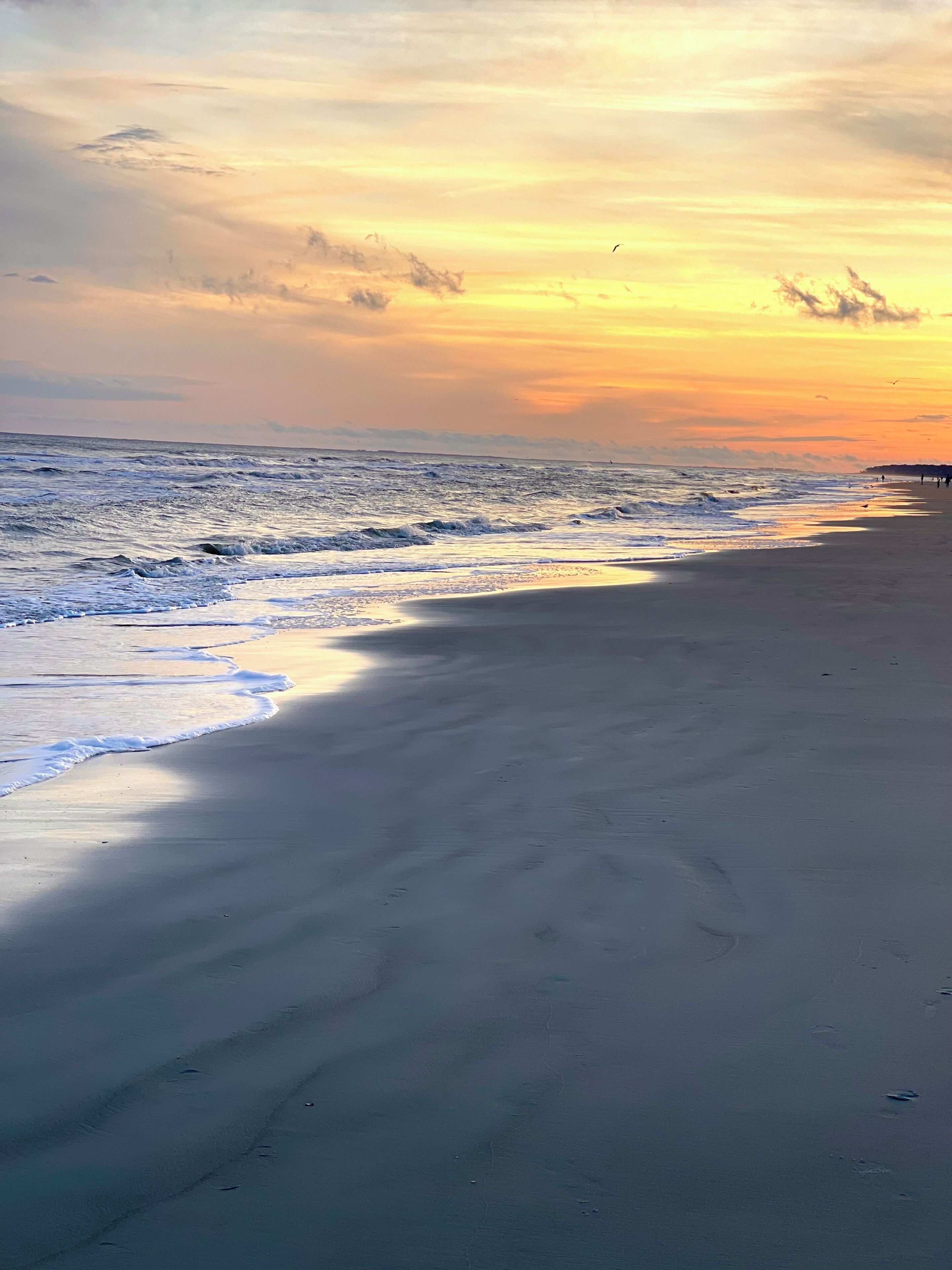 A beach with waves and a sunset.