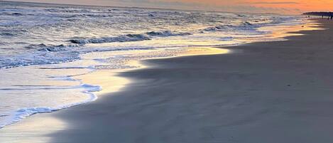 A beach with waves and a sunset.