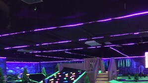 An indoor play area with a slide, climbing structures, and a small building with a letter 'J'. - Year round family fun (New Era)