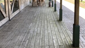 A covered wooden deck with tables and chairs, wooden beams, and a view of the outdoors. - Year round family fun (New Era)