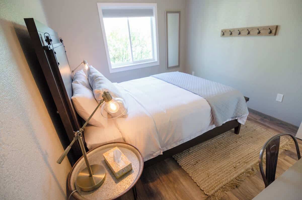 A bedroom with a bed, bedside lamp, and a window.