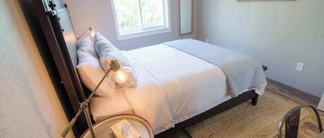 A bedroom with a bed, bedside lamp, and a window.