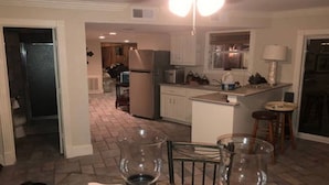 A kitchen with a central island, a dining area with chairs, and a refrigerator.