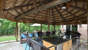 An outdoor patio with a thatched roof, a bar area, and seating.