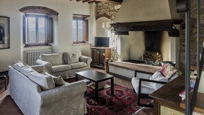 A cozy living room with a fireplace, a television, and comfortable seating. - Spacious home on beautiful Tuscan vineyard.  Near Florence. (Pelago)