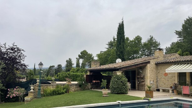 Una piscina con una casa de piedra y un jardín.