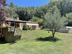 Une maison en pierre avec un toit en tuiles, un patio couvert et une pelouse bien entretenue.
