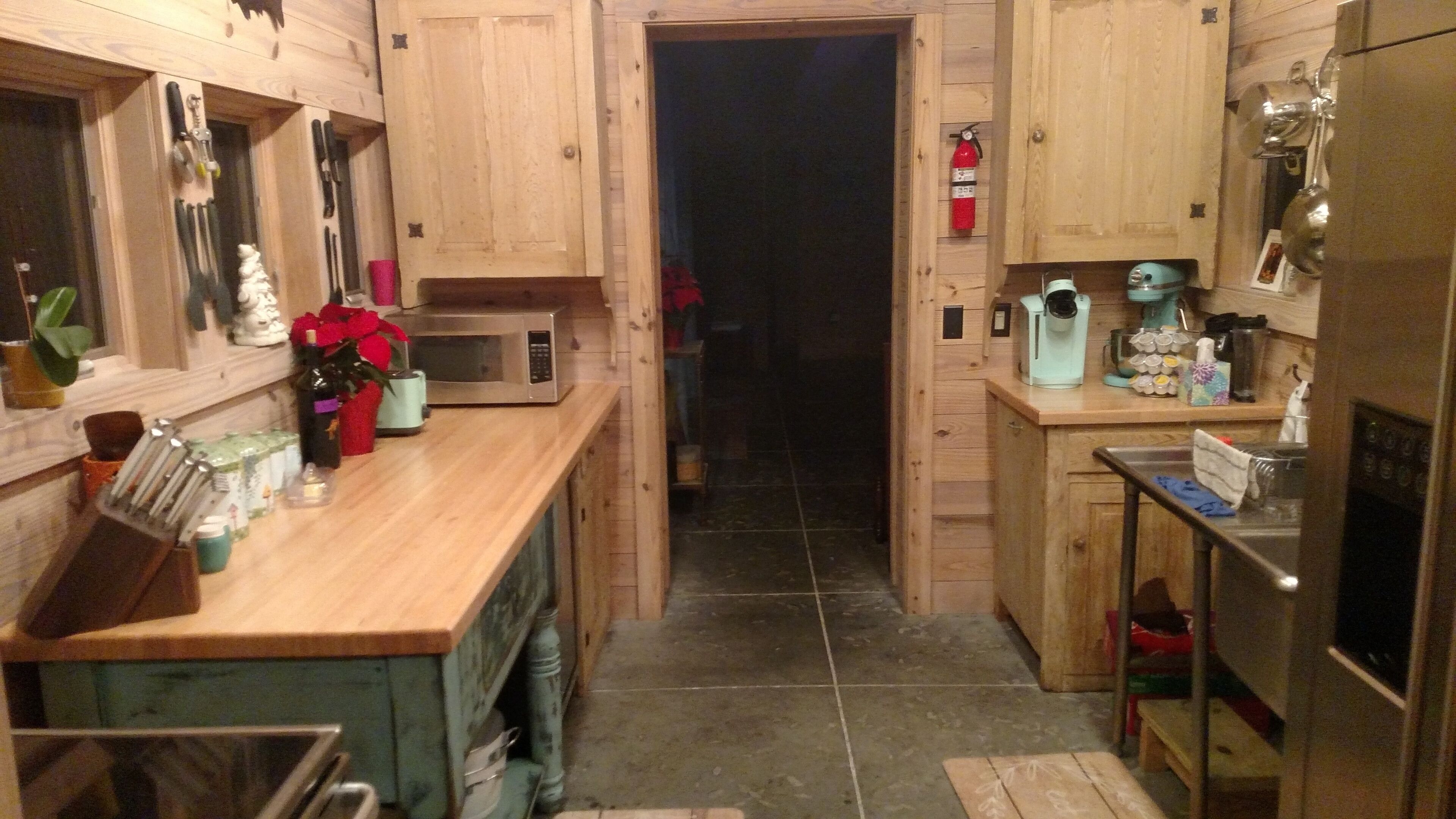 A narrow kitchen with wooden cabinets, a microwave, and a coffee maker.