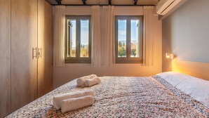 Un dormitori amb un llit, dues finestres amb cortines, un armari i un aparell d'aire condicionat.