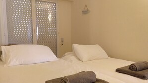 A hotel room with two beds, white linens, and rolled towels.